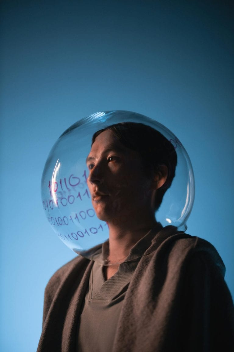 An artistic portrait with a transparent sphere and binary code on a blue background.
