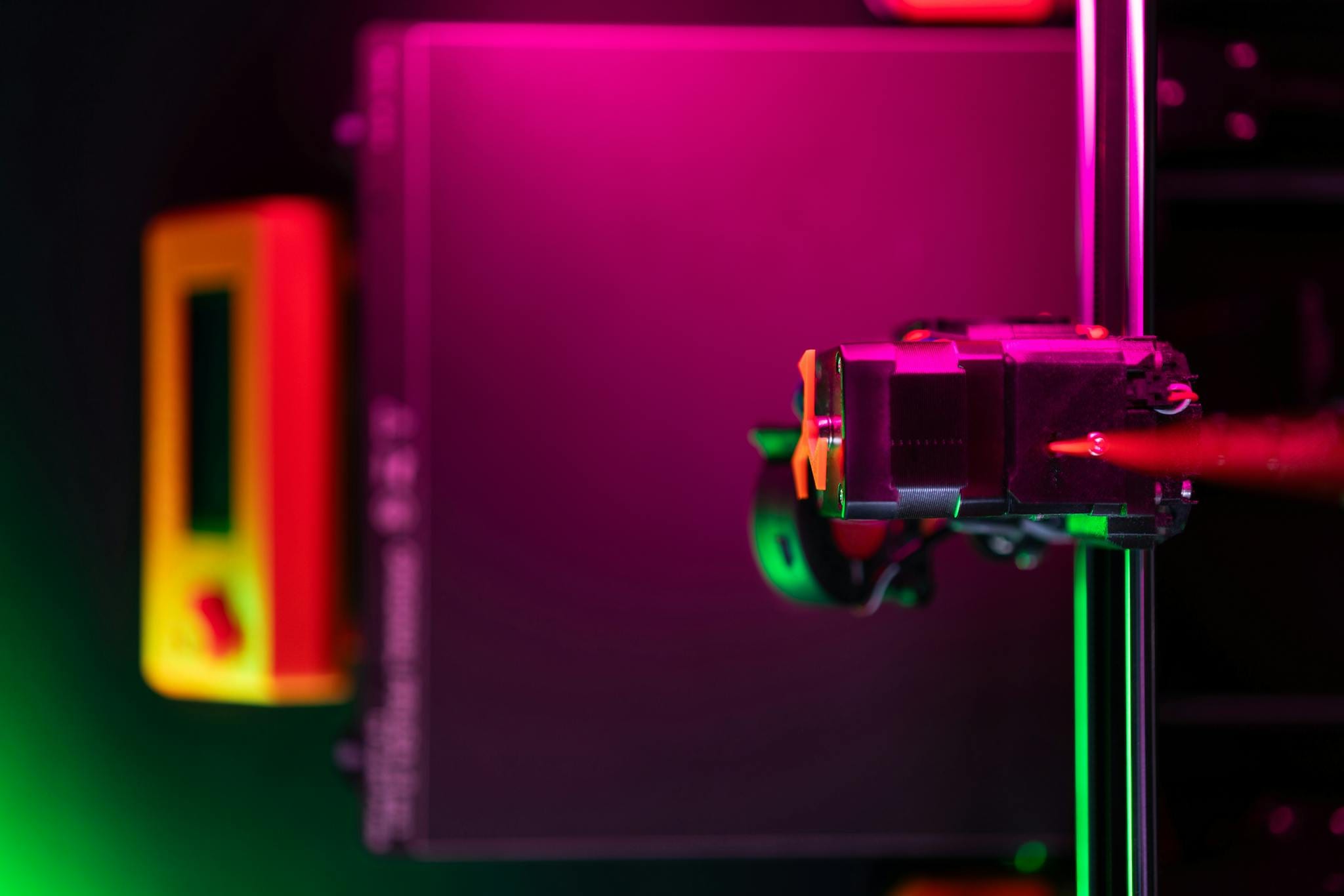Close-up of a 3D printer in neon lights with futuristic vibe.